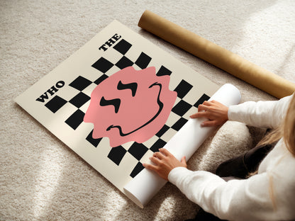 Person unrolling a large poster with a checkered design and pink circle on a light-colored floor.