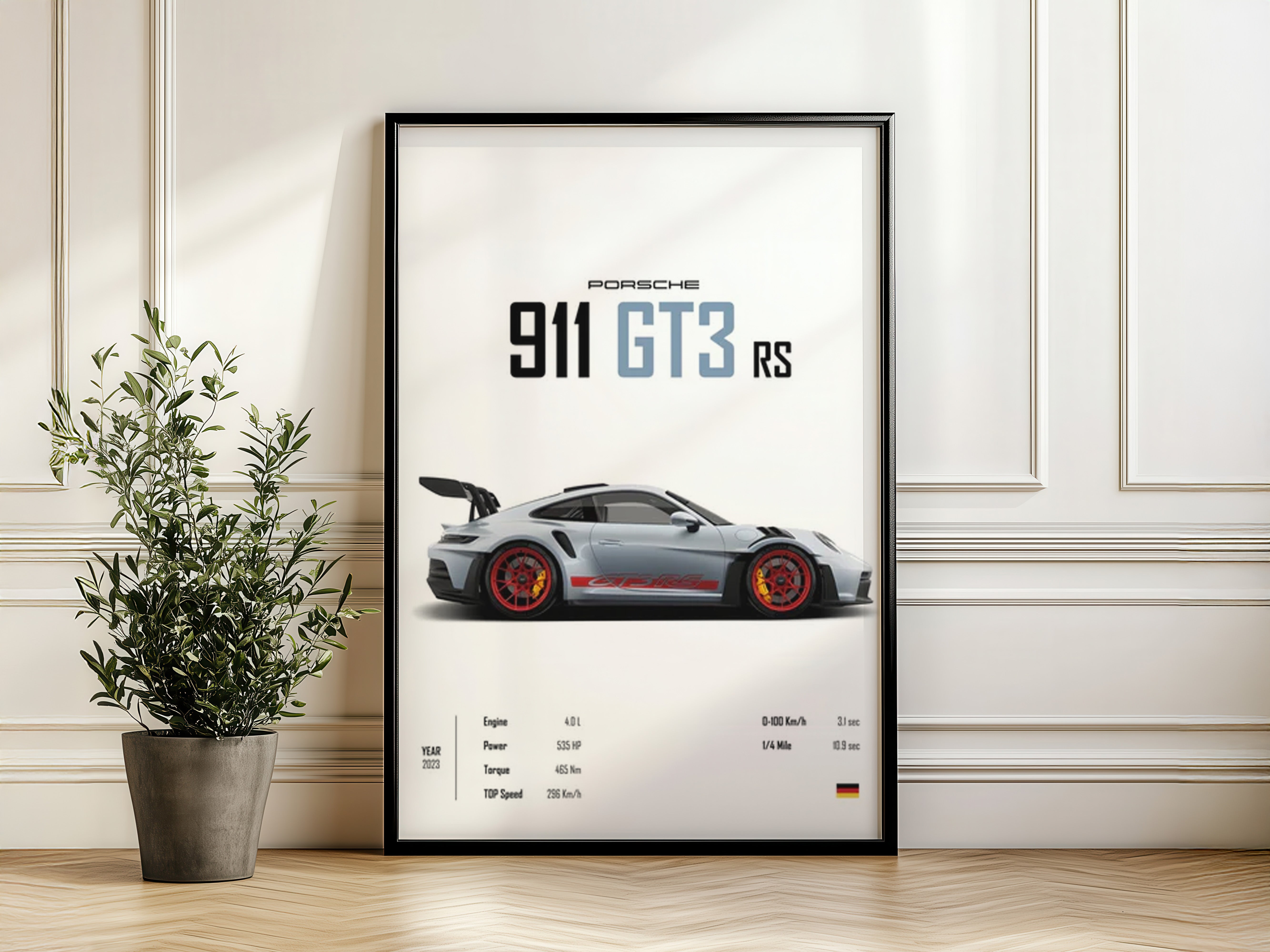 Framed poster of a Porsche 911 GT3 RS on a wall with a plant beside it.