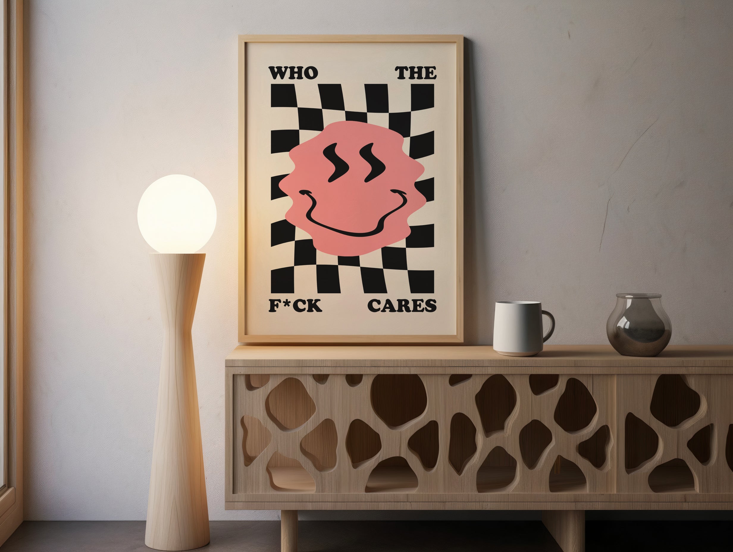 Framed poster with a pink smiley face and text on a wooden sideboard.