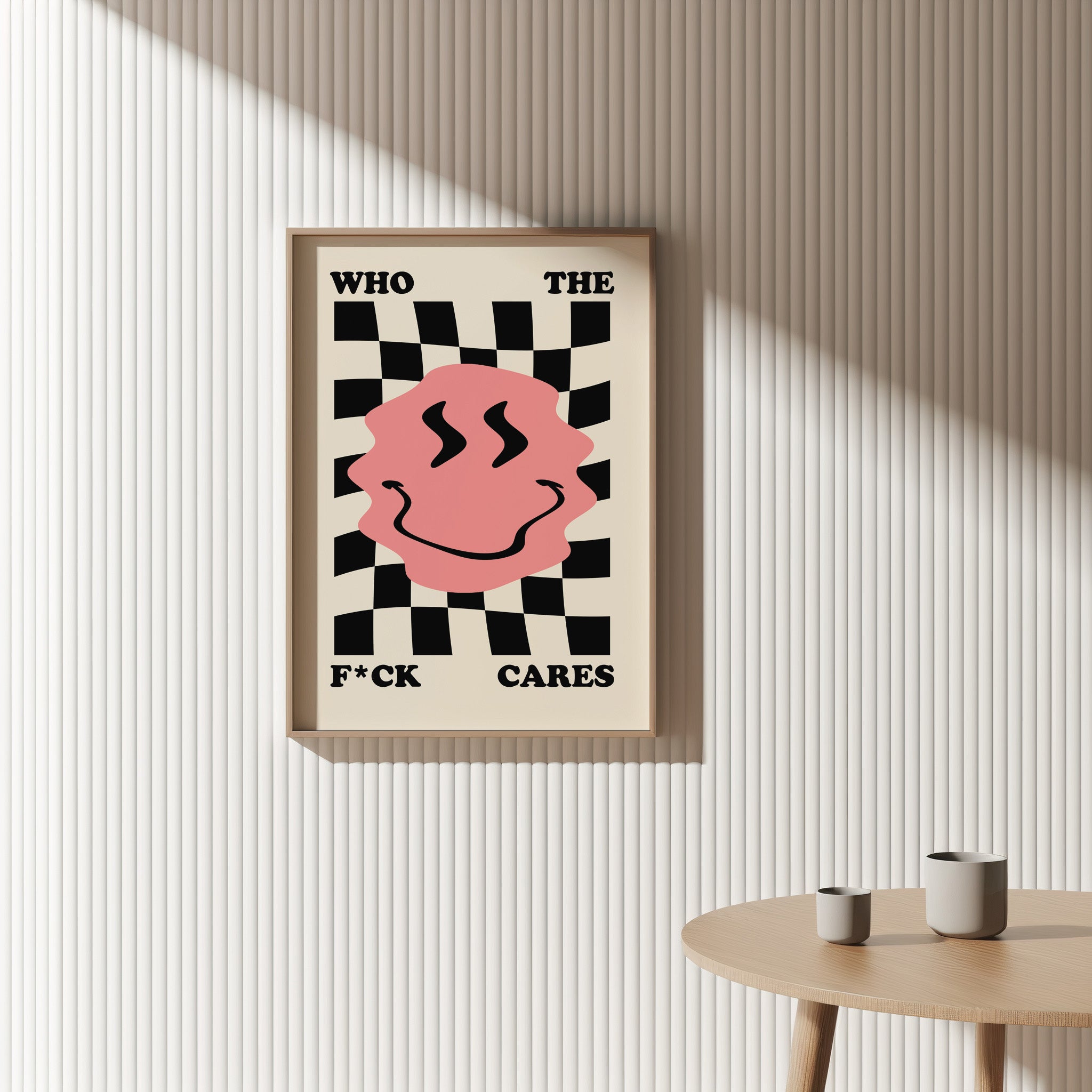 Framed poster with a pink smiley face and text on a wall with a table below.